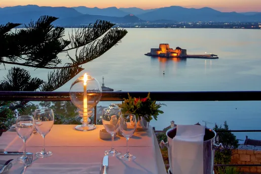 Outdoor patio with a dining table and wine glasses, with a view of a large lake