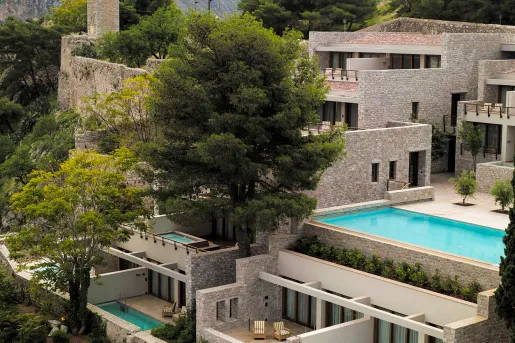 Exterior view of stone hotel building with mini outdoor pools