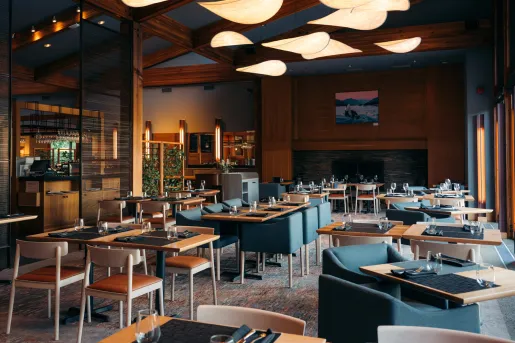 Restaurant dining hall with blue cushioned chairs in front of wooden dining tables