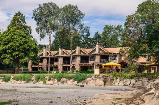 Exterior view of a hotel building with large windows, with tall trees surrounding the building