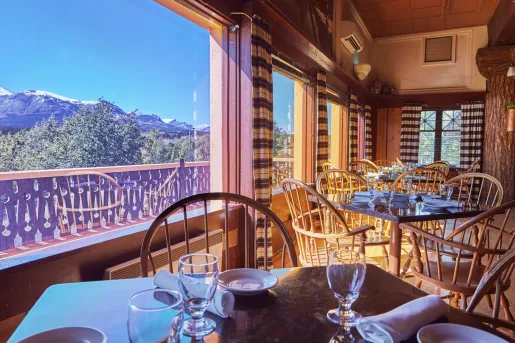 Dining hall with square tables next to large windows looking out to mountains