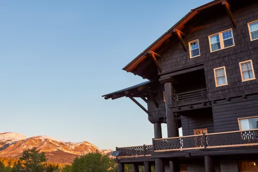 Exterior view of dark brown lodge building with mountains in the distance