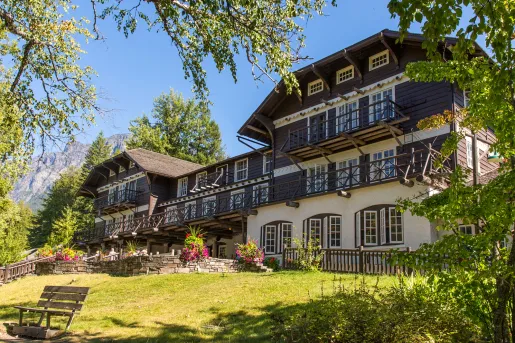 Exterior view of cabin-styled hotel building with a garden and staircase in front