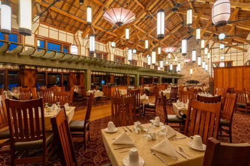 Large dining hall with skinny light fixtures and wooden chairs around each table