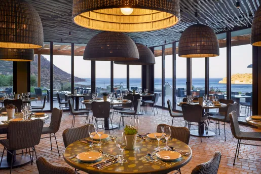 Dining hall with circular tables and woven chairs, with woven light fixtures