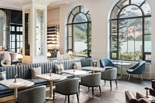 Hotel lounge with cushioned gray and blue chairs, with a bar in the back