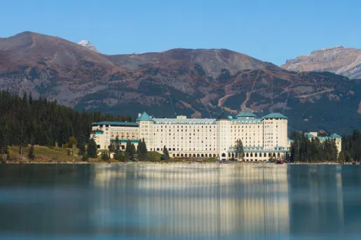 Large exterior view of a white and blue hotel building in front of a large lake