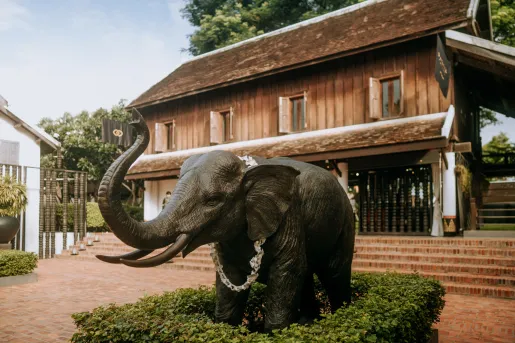 Exterior view of brown house with a bronze elephant statue in front
