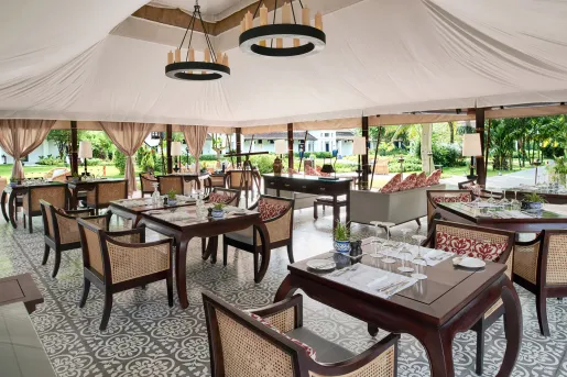 Outdoor dining area with large tent covering leading to a forest in the back