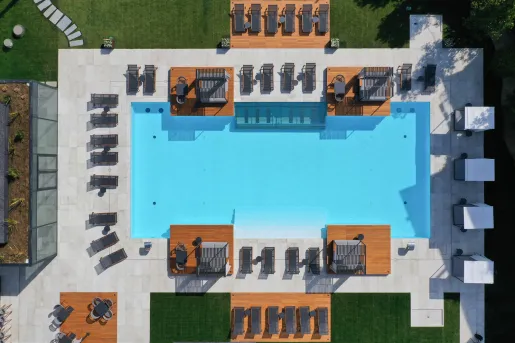 Sky view of an outdoor pool, surrounded by black chairs and wooden platforms
