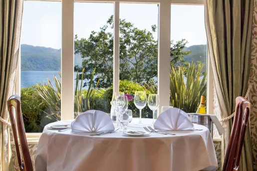 Circular dining table with wine glasses, next to a large opened window
