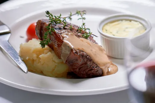 Plate of grilled steak and mashed potatoes, with a brown sauce on top