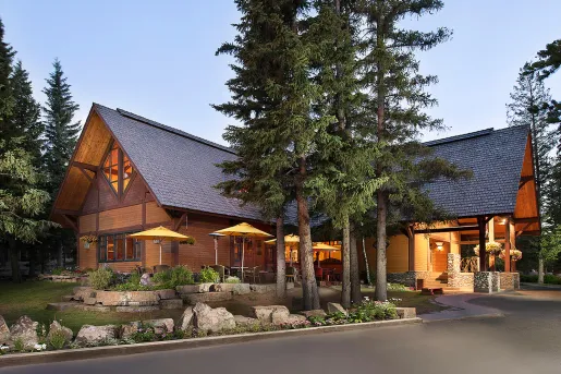 Exterior view of large wooden cabin, surrounded by tall trees