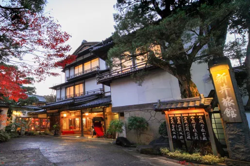 Exterior view of Japanese-style building with large trees and illuminated room