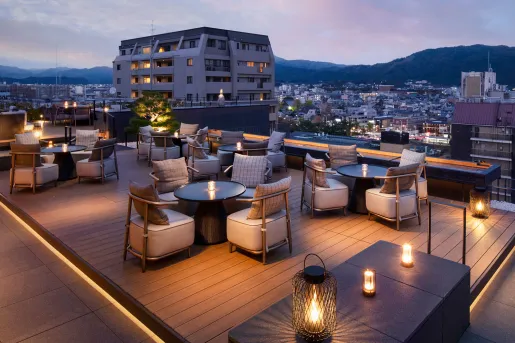 Hotel rooftop deck with cushioned chairs and circular tables