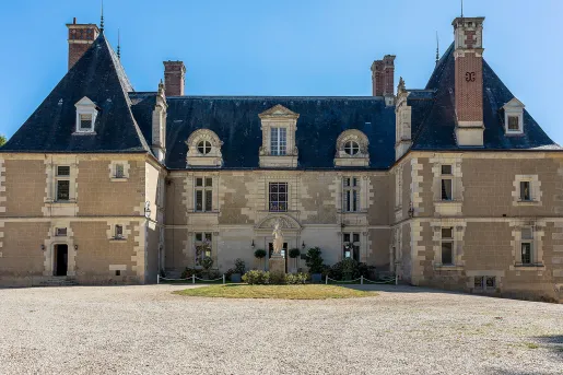 Exterior view of stone building with a gravel courtyard