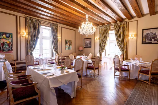 Indoor dining hall with a chandelier and tables with white tablecloths