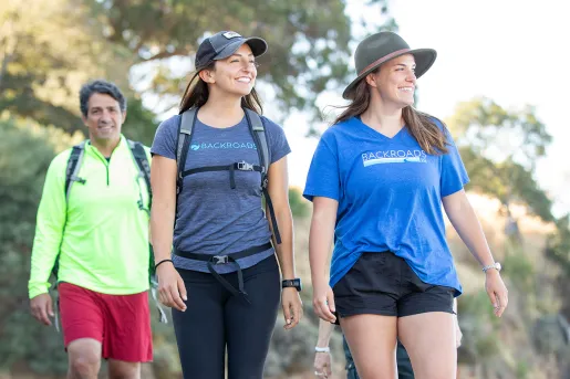 Group of men and women walking on a gravel trail, looking out to the left