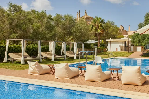 Outdoor pool with cushioned, reclining chairs and trees surrounding