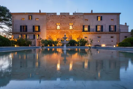Exterior view of  stone building with a large fountain in front