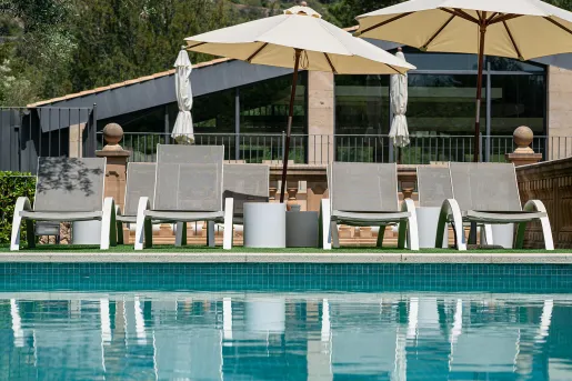 Outdoor pool with gray chairs and white umbrellas