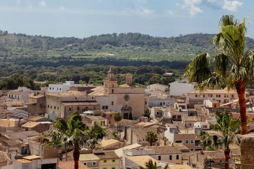 Sky view of town with beige houses and buildings, and a valley in the distance