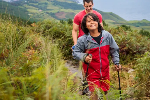 Man and boy hiking on a dirt trail with mountains in the distance
