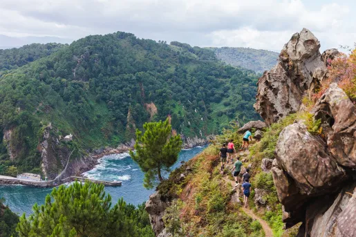 Group of people hiking on a dirt trail on a hill with a river on the ground floor