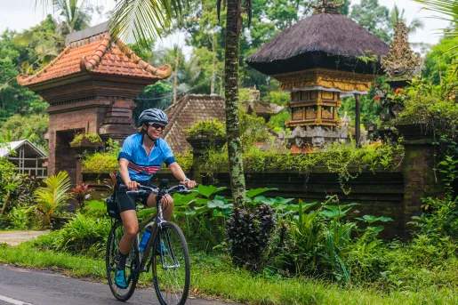 Woman riding a bike with brick buildings and grass in the background