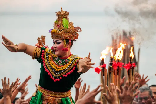 Woman wearing a traditional dress and makeup dancing above a group of people