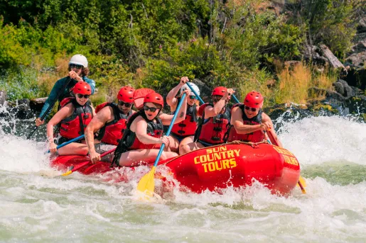 Group of people paddling on a red raft in a river