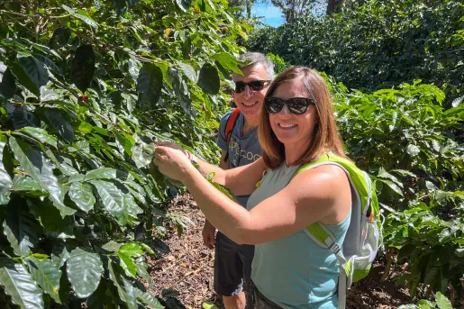 Man and woman wearing sunglasses, smiling while picking berries