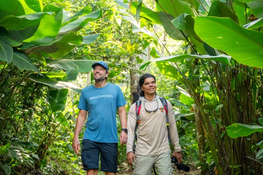 Two men smiling while walking through a jungle