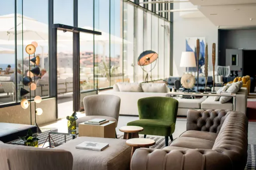 Room with large glass walls, looking out to an outdoor patio with white umbrellas