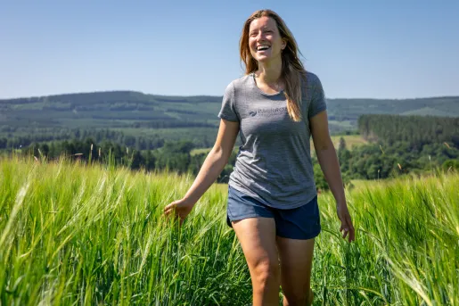 Woman smiling, while walking through a grassy field