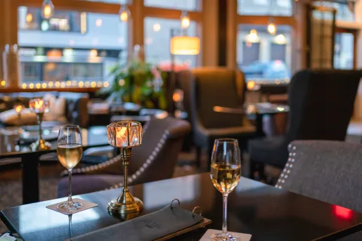 Black table with two wine glasses and a small light fixture on the table