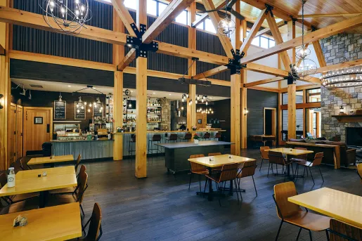 Restaurant and bar with wooden tables along the walls and large wooden pillars