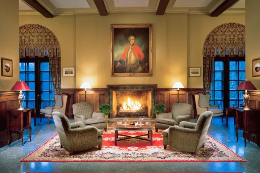 Hotel lobby, with cushioned chairs in front of a lit fireplace