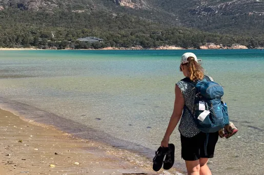 Woman holding her sandals while walking along a beach