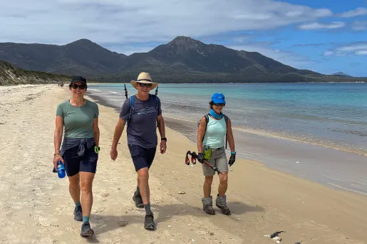 Man and two women walking along a beach