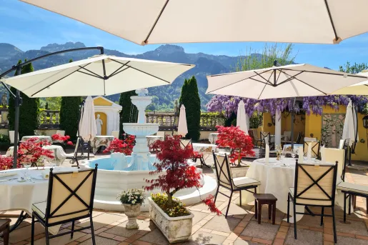 Outdoor patio with dining tables and a stone fountain in the center