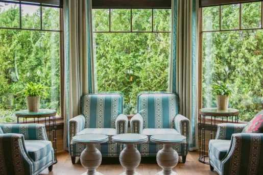 Room with large windows and green and white chairs along the walls
