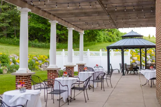 Outdoor patio with white dining tables and black, metal chairs