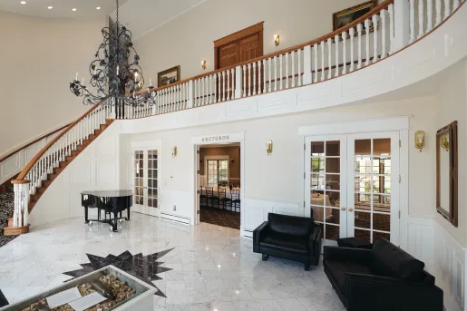 Large lobby white room with black sofas and a piano in the corner