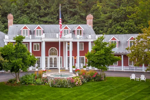 Exterior view of red and white building with an American flag and grass field in front