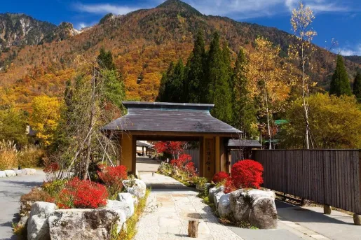 Stone pathway with a wooden archway, surrounded by large boulders and tall mountains in the distance