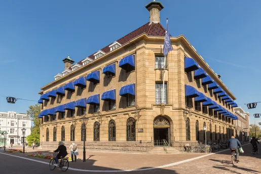 Exterior view of of stone, 2 story building with blue coverings over the windows