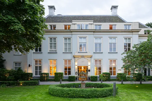 Exterior view of white two-story building with a grass field in front