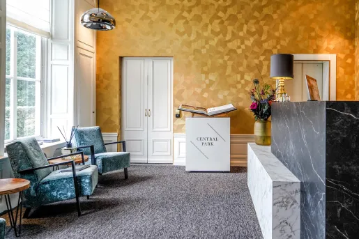 Hotel lobby with blue cushioned chairs and a marble counter to the right