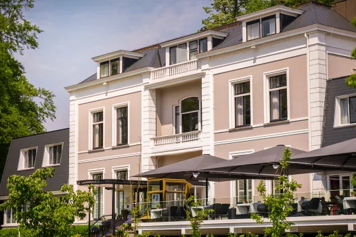 Exterior view of beige colored building with outdoor patio with gray umbrellas